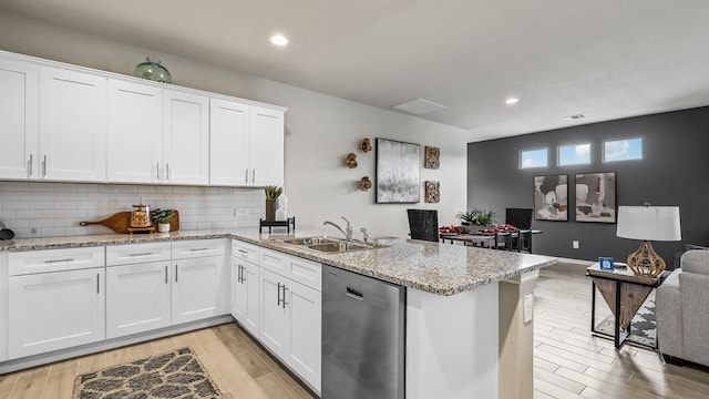 kitchen with light hardwood / wood-style flooring, kitchen peninsula, dishwasher, backsplash, and sink