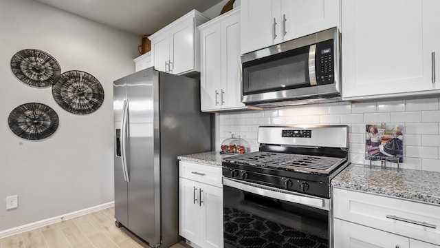 kitchen featuring light hardwood / wood-style flooring, decorative backsplash, stainless steel appliances, and light stone countertops