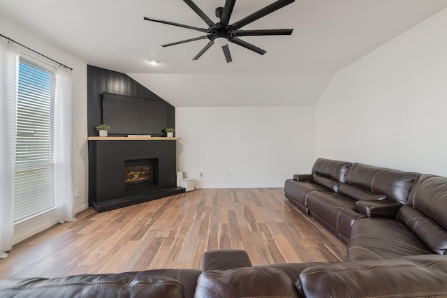 living room with lofted ceiling, light wood-style flooring, a fireplace, and ceiling fan