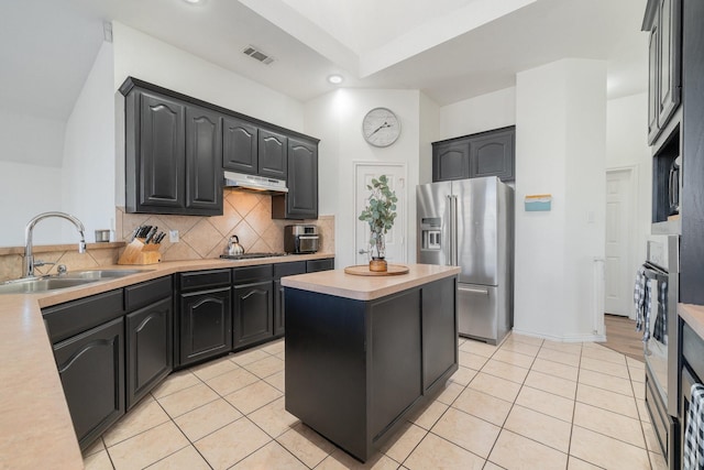 kitchen featuring light tile patterned floors, decorative backsplash, appliances with stainless steel finishes, a sink, and under cabinet range hood