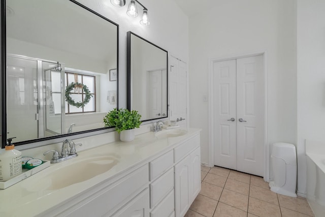 bathroom featuring tile patterned flooring, double vanity, a sink, and a bath