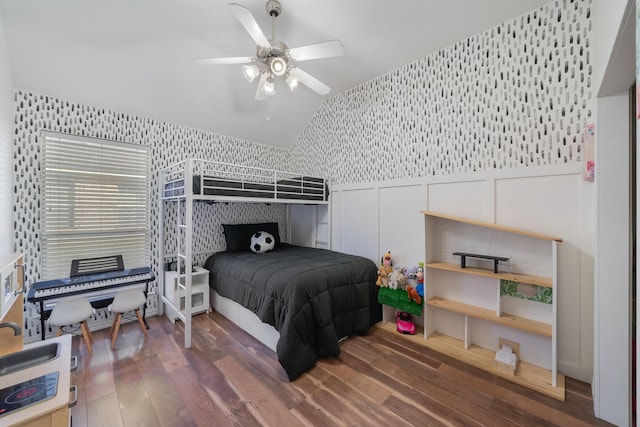 bedroom featuring ceiling fan, lofted ceiling, a decorative wall, a wainscoted wall, and wood finished floors