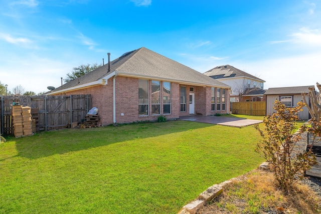 back of property featuring brick siding, a yard, a patio, a fenced backyard, and an outdoor structure