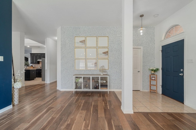 entryway with baseboards, wood finished floors, and wallpapered walls