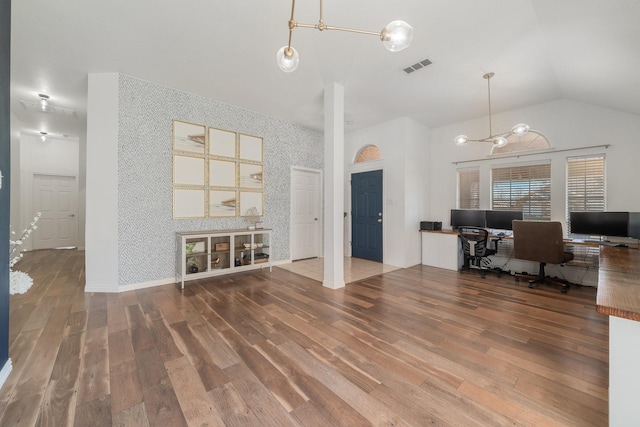 unfurnished office with high vaulted ceiling, visible vents, wallpapered walls, and wood finished floors