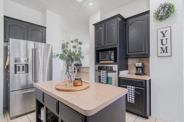 kitchen featuring stainless steel appliances, tasteful backsplash, light countertops, light tile patterned flooring, and a kitchen island