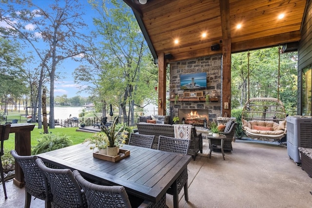 view of patio / terrace featuring an outdoor stone fireplace, a water view, and central AC unit