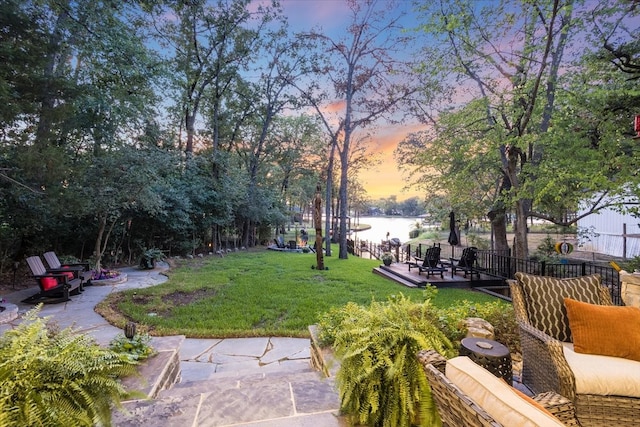 yard at dusk featuring a water view and a patio area