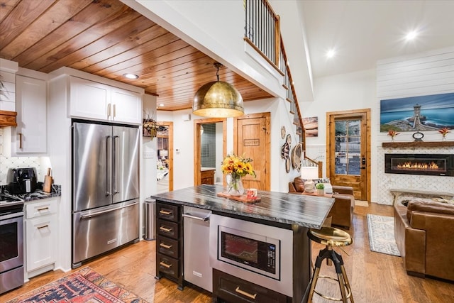 kitchen with white cabinets, pendant lighting, a kitchen island, stainless steel appliances, and a kitchen bar