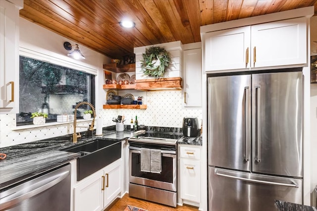 kitchen featuring dark stone counters, white cabinetry, sink, and stainless steel appliances