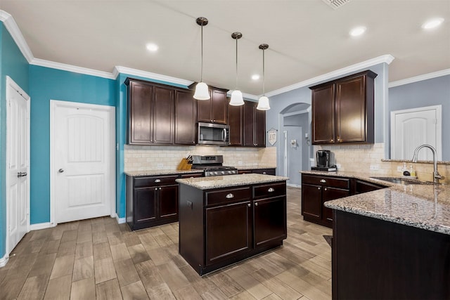 kitchen featuring hanging light fixtures, decorative backsplash, appliances with stainless steel finishes, dark brown cabinets, and sink