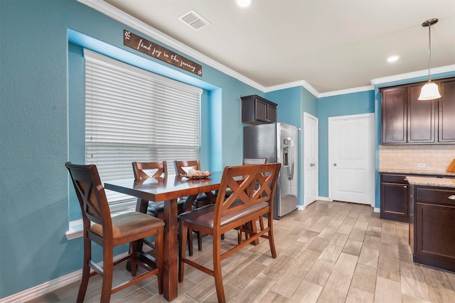 dining space with light wood-type flooring and ornamental molding