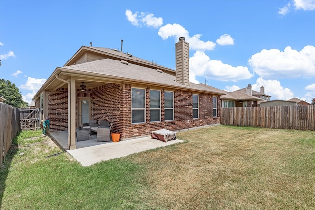 rear view of property featuring ceiling fan, a patio area, and a yard