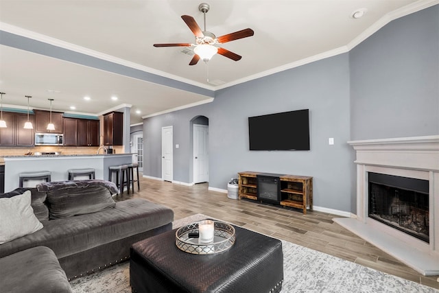 living room with light hardwood / wood-style flooring, crown molding, and ceiling fan