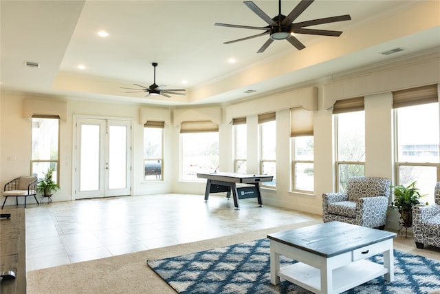 tiled living room with ceiling fan, french doors, and a tray ceiling