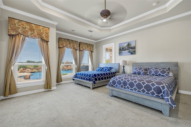 bedroom featuring a tray ceiling, ceiling fan, ornamental molding, and carpet