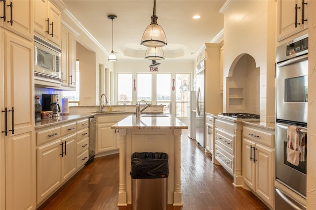 kitchen featuring dark hardwood / wood-style flooring, light stone countertops, stainless steel appliances, pendant lighting, and a center island with sink