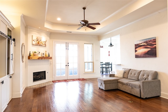 living room featuring french doors, dark hardwood / wood-style floors, a tray ceiling, ceiling fan, and crown molding