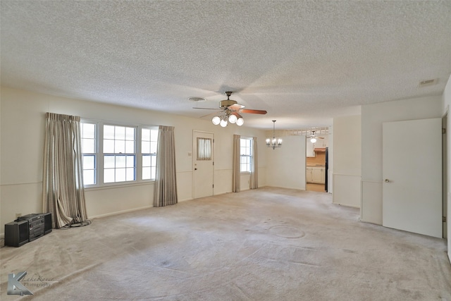 unfurnished living room featuring ceiling fan with notable chandelier, a textured ceiling, and light colored carpet