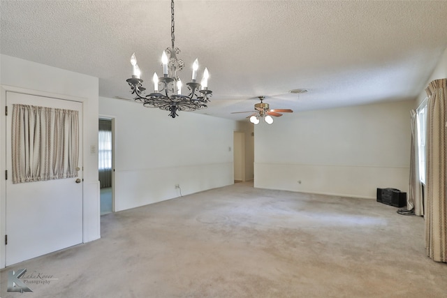 unfurnished room featuring a textured ceiling, plenty of natural light, light colored carpet, and ceiling fan with notable chandelier