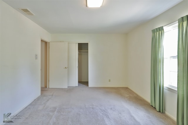 unfurnished bedroom featuring light colored carpet and a closet