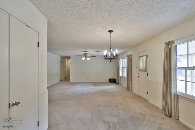 carpeted spare room with ceiling fan with notable chandelier and a textured ceiling