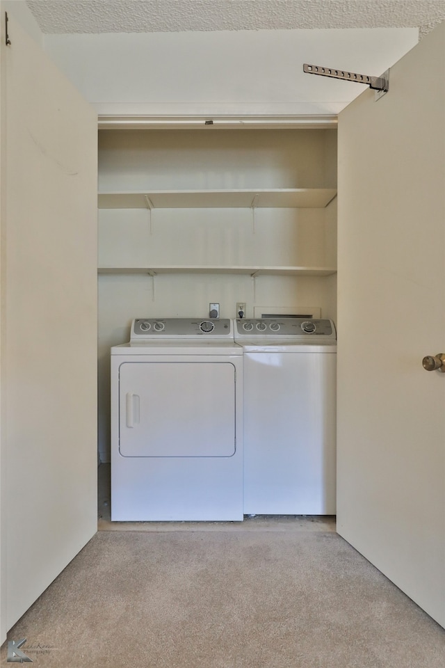 laundry room featuring light carpet, washing machine and dryer, and a textured ceiling