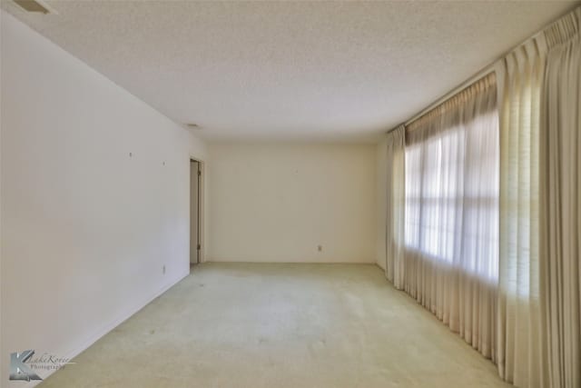 carpeted empty room featuring a textured ceiling