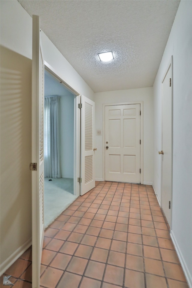 entryway with a textured ceiling and light tile patterned floors