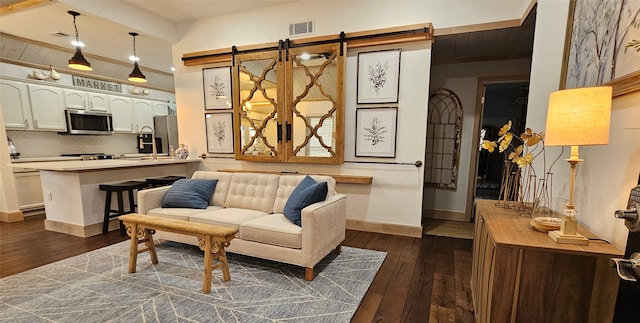 living room featuring a barn door and dark wood-type flooring