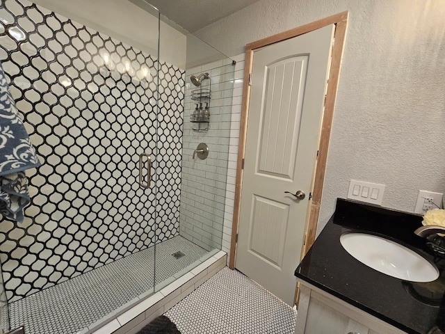 bathroom featuring a shower with door and vanity