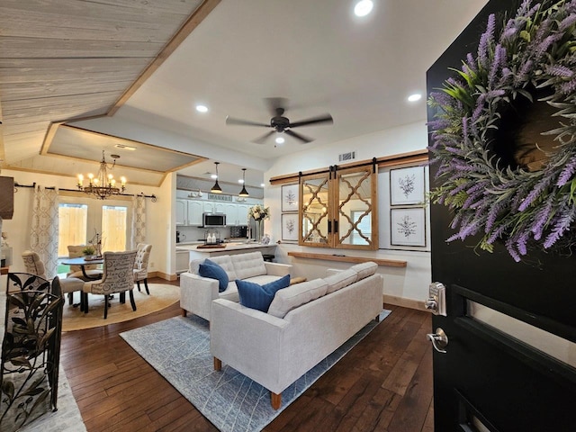 living room with a barn door, dark hardwood / wood-style floors, and ceiling fan with notable chandelier