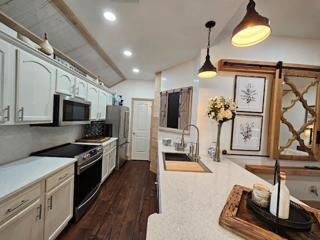 kitchen with dark hardwood / wood-style floors, stainless steel appliances, a barn door, decorative light fixtures, and tasteful backsplash