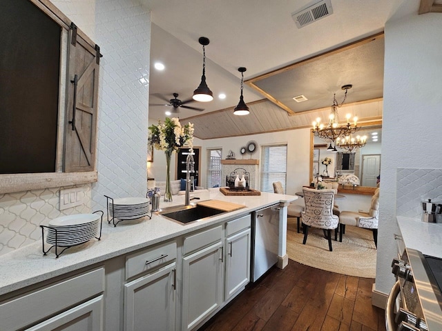 kitchen featuring a barn door, dark wood-type flooring, dishwasher, and decorative light fixtures