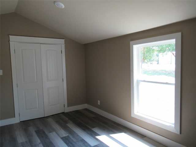 unfurnished bedroom with dark hardwood / wood-style floors, lofted ceiling, and a closet