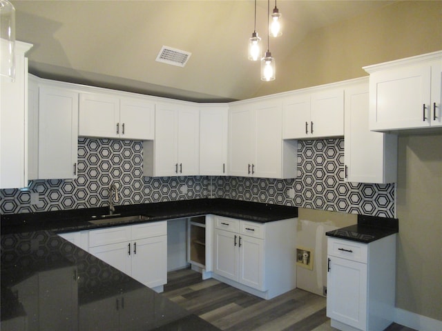 kitchen featuring dark hardwood / wood-style flooring, hanging light fixtures, white cabinets, vaulted ceiling, and sink