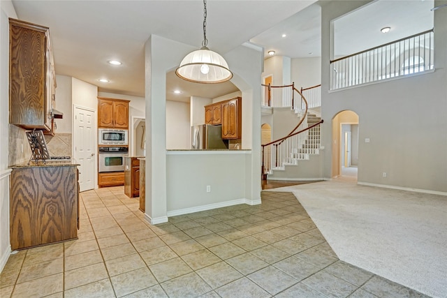 kitchen featuring light carpet, backsplash, stainless steel appliances, arched walkways, and light tile patterned floors