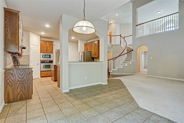 kitchen featuring decorative backsplash, stainless steel appliances, hanging light fixtures, and light colored carpet