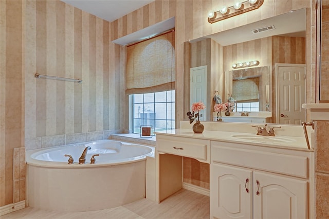 bathroom featuring a bath, visible vents, wallpapered walls, and vanity