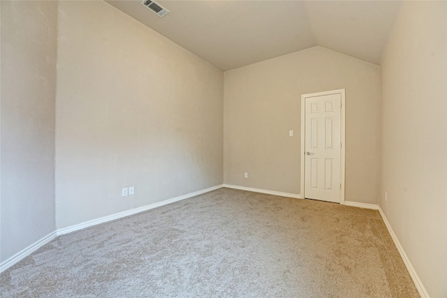 carpeted spare room featuring visible vents, baseboards, and vaulted ceiling