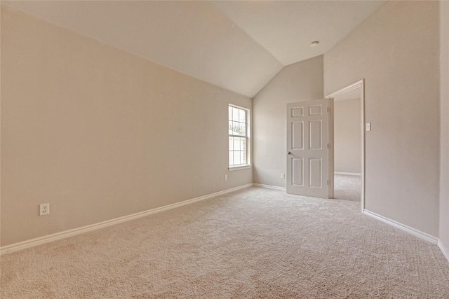 carpeted empty room featuring baseboards and lofted ceiling