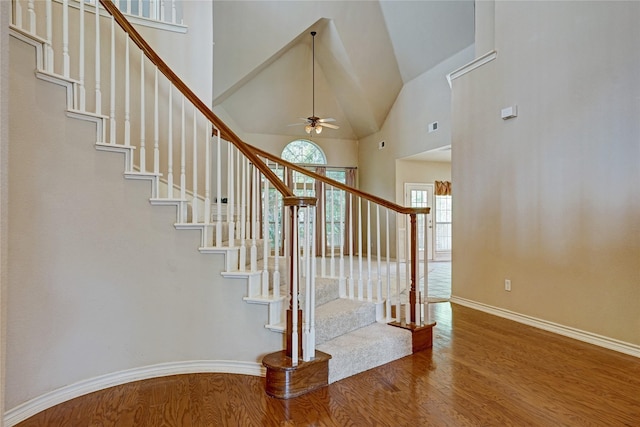 stairs with visible vents, a ceiling fan, wood finished floors, high vaulted ceiling, and baseboards