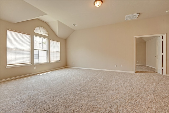 empty room featuring light colored carpet and vaulted ceiling