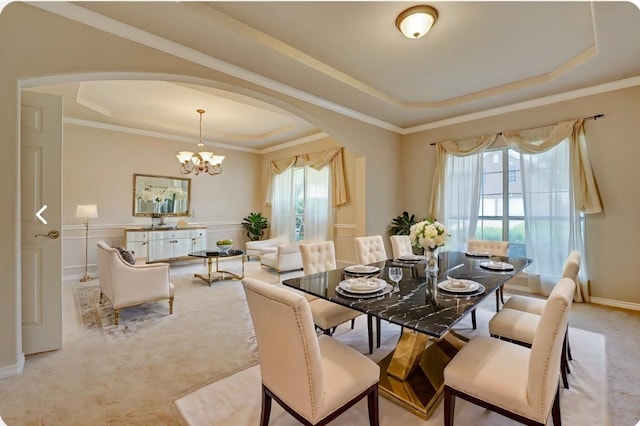 dining area with a tray ceiling, arched walkways, light colored carpet, and crown molding