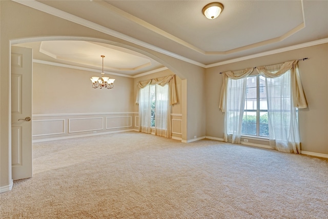 unfurnished room with a tray ceiling, light carpet, a chandelier, and ornamental molding