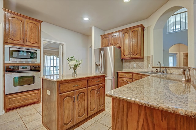 kitchen featuring light tile patterned floors, decorative backsplash, appliances with stainless steel finishes, and a center island