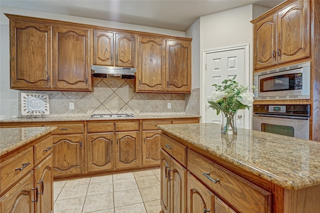 kitchen featuring decorative backsplash, appliances with stainless steel finishes, light tile patterned floors, and light stone countertops