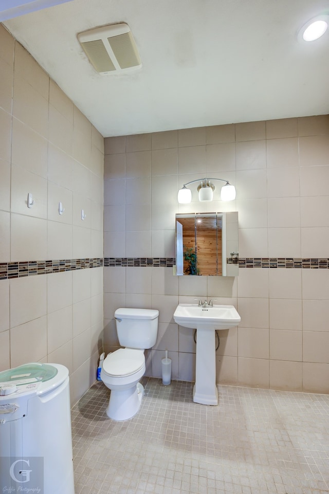 bathroom featuring tasteful backsplash, tile walls, toilet, and tile patterned flooring