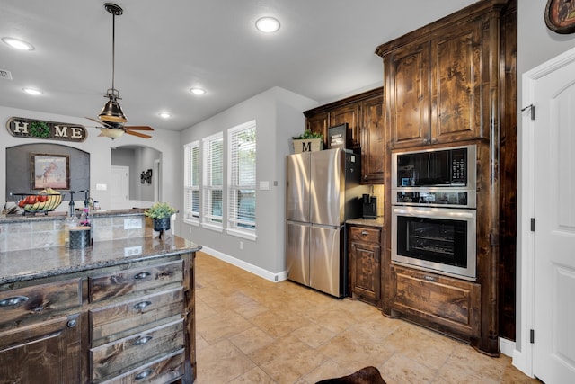 kitchen featuring ceiling fan, stainless steel appliances, dark brown cabinetry, and stone countertops