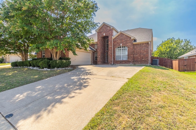 view of front of house with a front lawn, cooling unit, and a garage